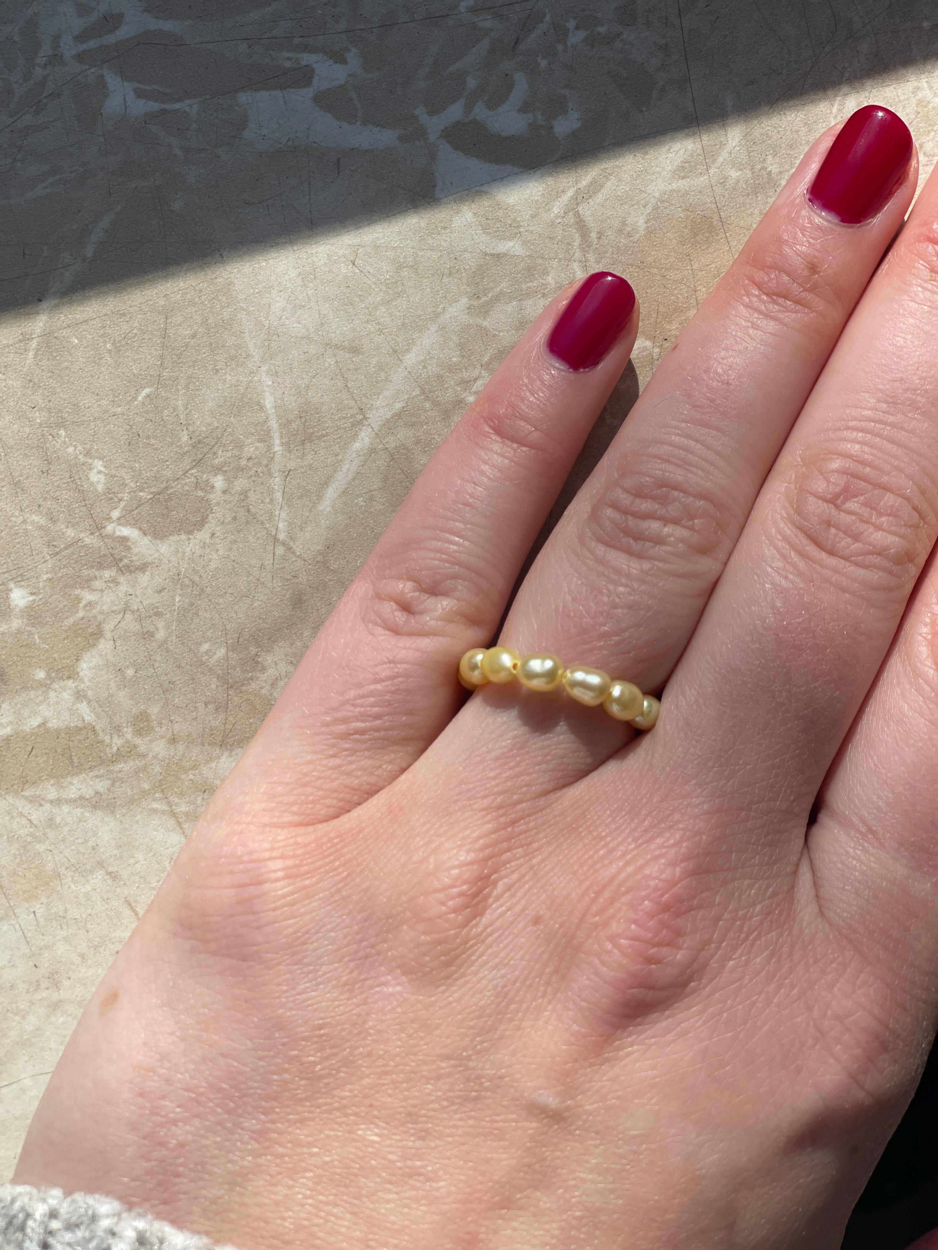 Elastischer Perlenring gelb am FInger fotografiert